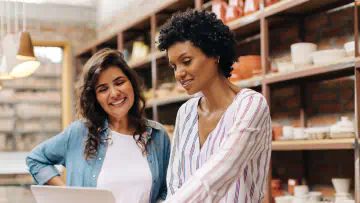 Two women look at a laptop